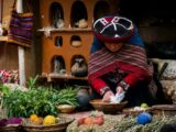 Quechua woman in traditional dress demonstrating natural textile dyeing in Chinchero