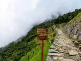 Trail sign pointing to the Sun Gate along the stone path of the Inca Trail