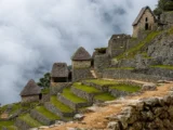 Thatched-roof stone houses along the terraced slopes of Machu Picchu