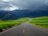 Scenic road through the green farmland of the Sacred Valley with mountains ahead
