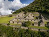Stone plazas and roofless buildings of the Choquequirao Inca citadel surrounded by clouds