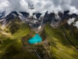 Drone view of turquoise Humantay Lake nestled below glacier-capped mountains