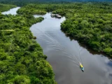 Aerial view of a boat navigating the Manu River through the Amazon rainforest