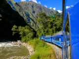 Blue PeruRail train winding along the Urubamba River toward Machu Picchu