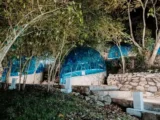 Illuminated blue geodesic glamping domes built on stone terraces among trees at night on the Salkantay route