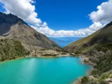 Turquoise water of Humantay Lake surrounded by steep andean slopes under a blue sky with white clouds