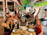 Trekking group raising drinks around a long table of shared dishes at a lodge on the Salkantay Trek