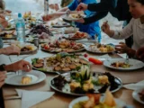 Long table covered with shared plates of andean food while the cooking crew serves the trekking group