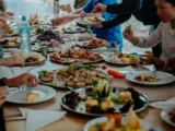 Long table covered with shared plates of andean food while the cooking crew serves the trekking group