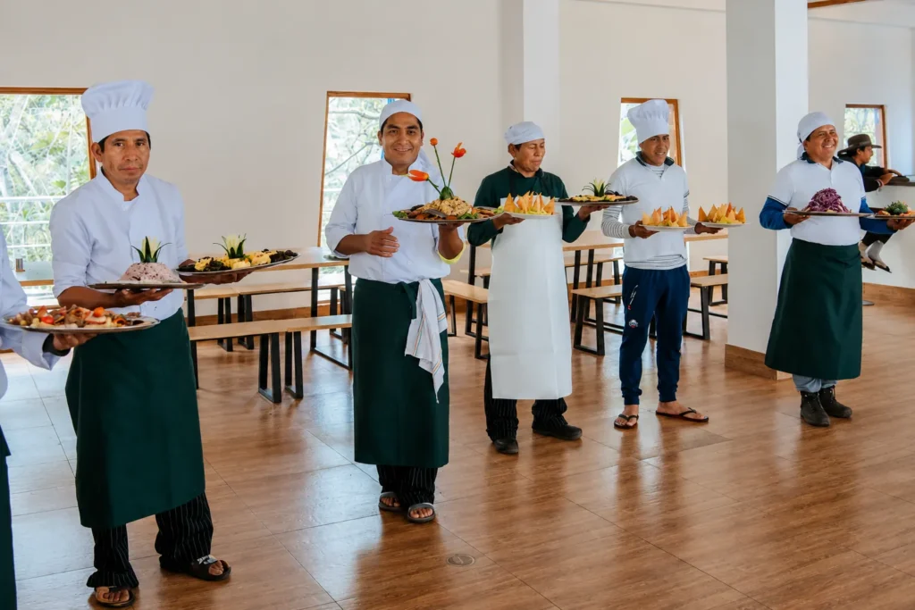 Andean Moments trekking cooks in chef uniforms presenting decorated platters of food