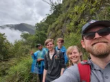 Hikers and guide smiling on a misty cloud forest path on the Inca Jungle Trail