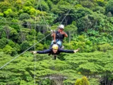 Traveler flying on a zip line above the lush jungle canopy on the Inca Jungle Trail