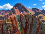 Viajera de pie sobre las franjas rojas, grises y verdes de Pallay Punchu