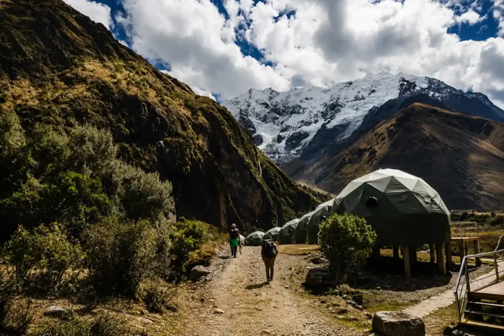 Salkantay Trek hikers approaching the dome campsite with the Salkantay mountain in the background