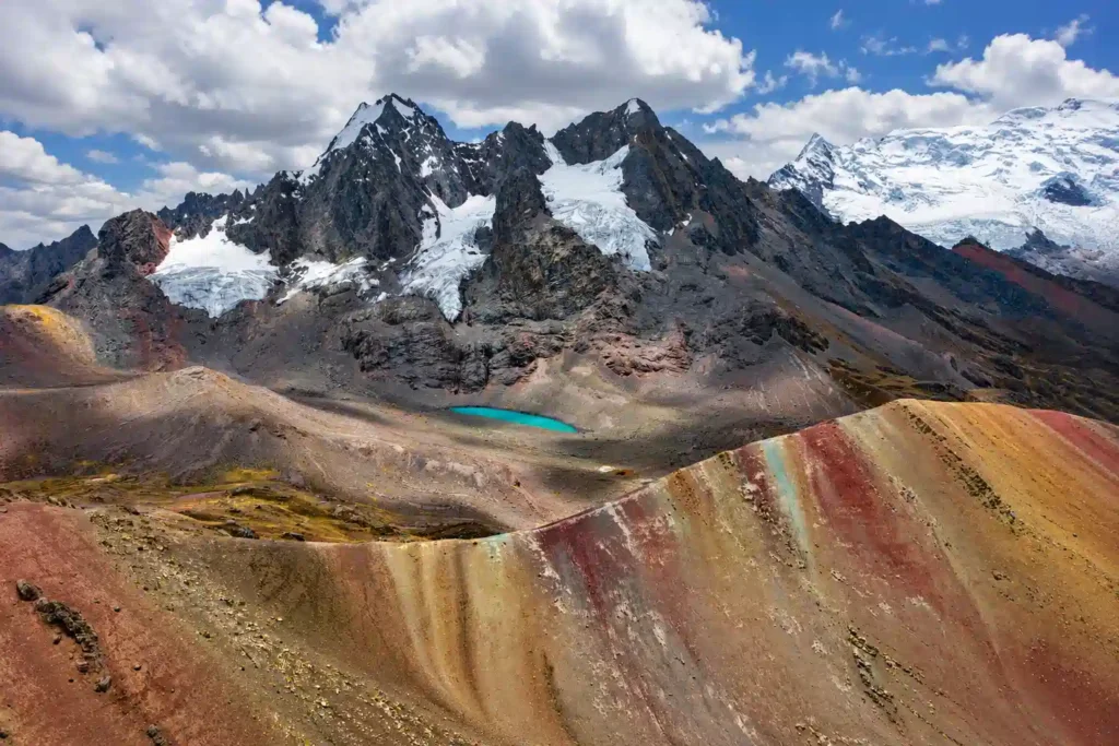 Snow capped peaks of the Ausangate massif rising above a turquoise glacial lake near Rainbow Mountain