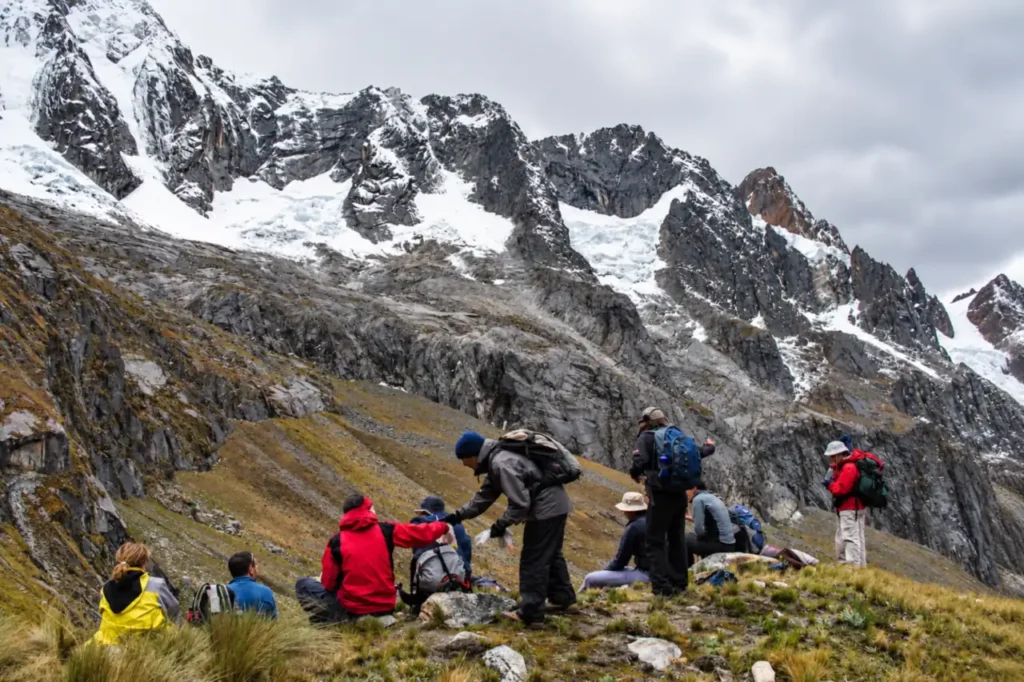 Hikers resting below the glaciers of the Cordillera Blanca on the Santa Cruz Trek