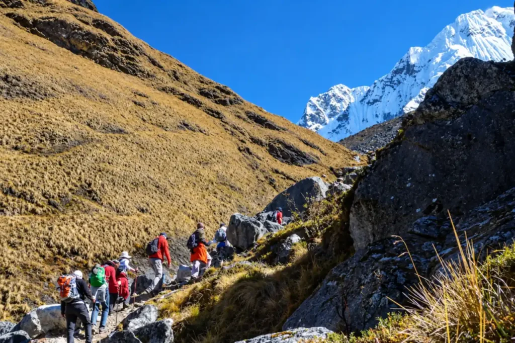 Hikers climbing the rocky trail to the Salkantay Pass with Nevado Salkantay behind