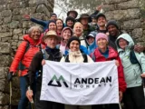 Hikers with the Andean Moments flag at Inca stone ruins on a misty day of the Inca Trail