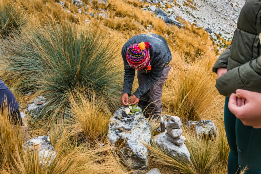 Guide placing coca leaves on an apacheta as a k'intu offering on the Salkantay Trek