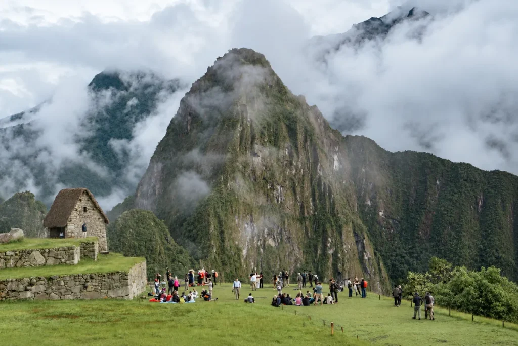 Neblina matinal sobre el Huayna Picchu con visitantes en la plaza principal de Machu Picchu