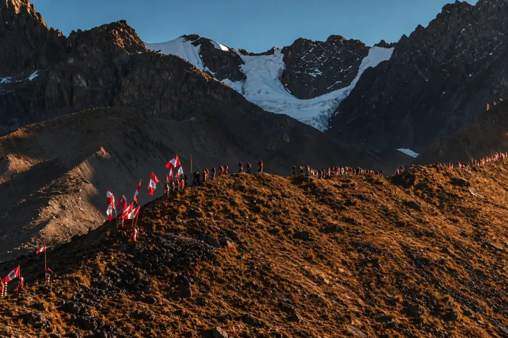 Peregrinos de Qoyllority (Qoyllur Rit'i) con banderas del Perú en una cresta bajo el glaciar de Sinakara