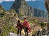 Casal de poncho no mirante clássico de Machu Picchu num pacote privado, com o Huayna Picchu atrás