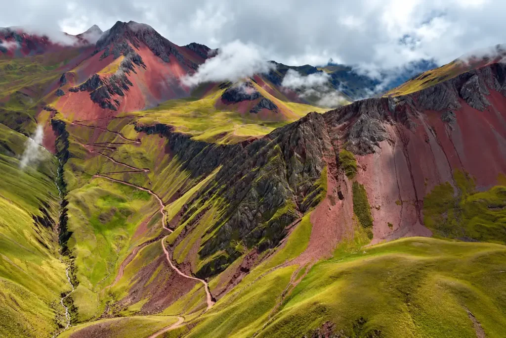 Pallay Punchu trail winding up a green valley between red slopes