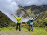 Two hikers with open arms at a cloud forest viewpoint on the Short Inca Trail